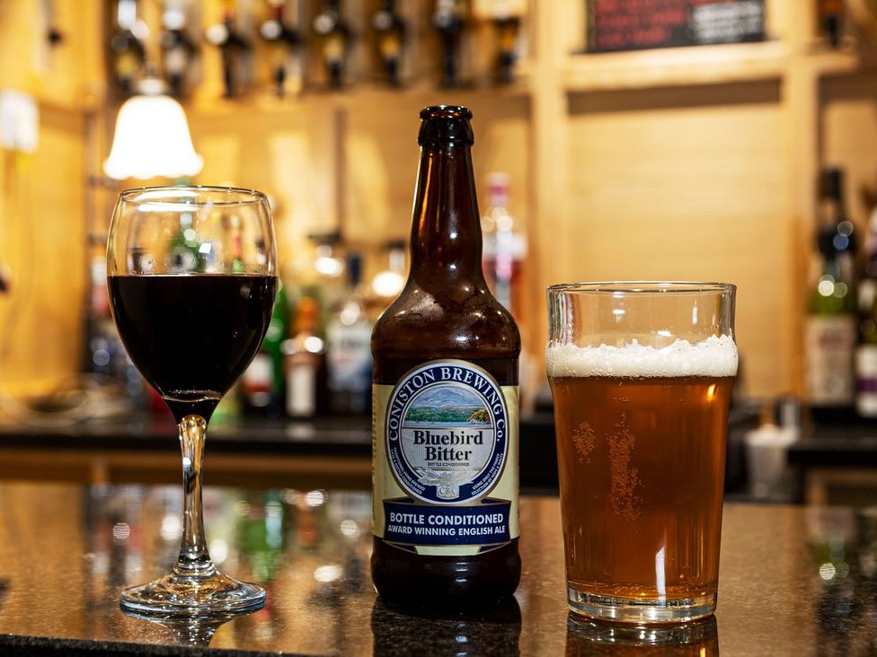 Two glasses and a beer bottle on a bar countertop at Lonsdale House Bowness-On-Windermere