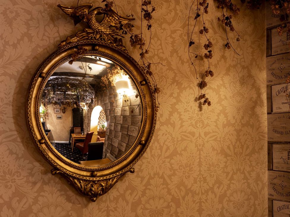 A mirror reflecting a hallway with a chair at Lonsdale House in Bowness-On-Windermere