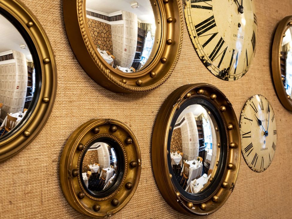 A wall with clocks and mirrors at Lonsdale House Bowness-On-Windermere