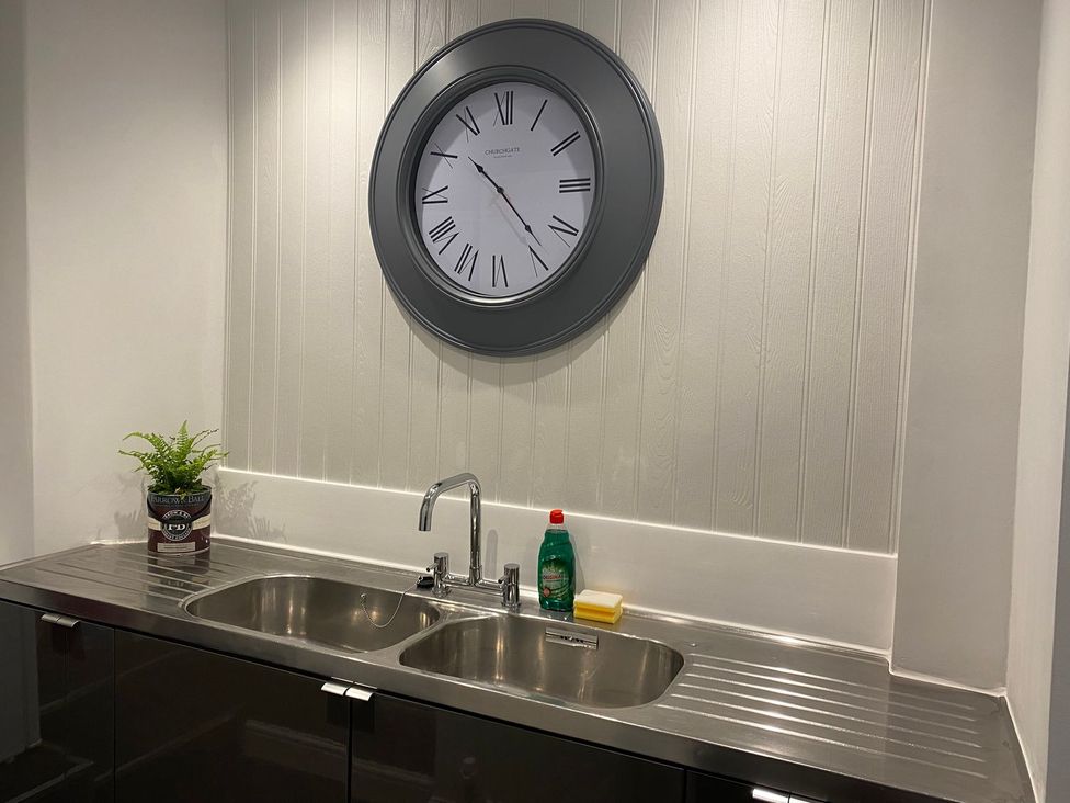 A kitchen with a sink and clock at Lonsdale House Bowness-On-Windermere