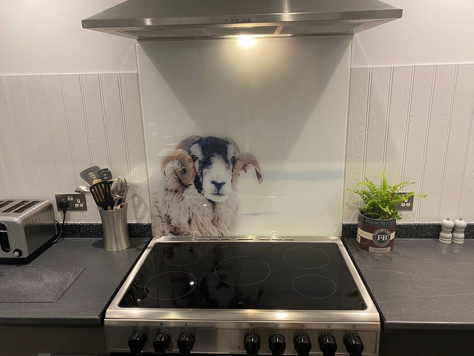 A kitchen featuring a stove and a splashback with a sheep design at Lonsdale House Bowness-On-Windermere