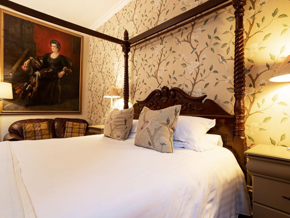 A bedroom with a four-poster bed and wall art at Lonsdale House Bowness-On-Windermere