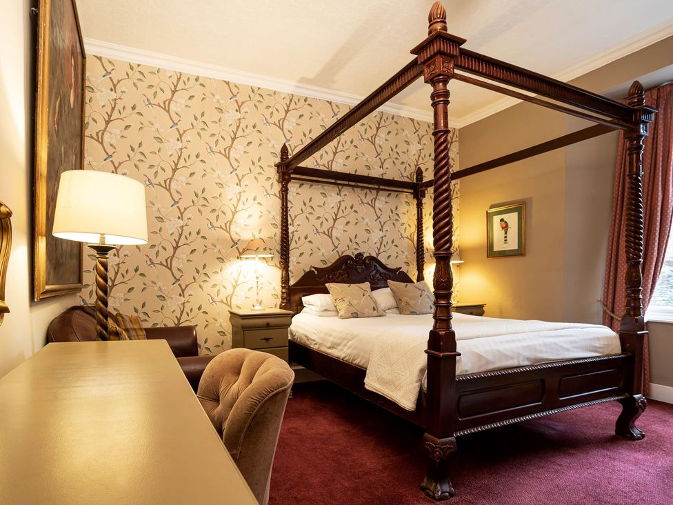 A bedroom with a four-poster bed and desk at Lonsdale House in Bowness-On-Windermere