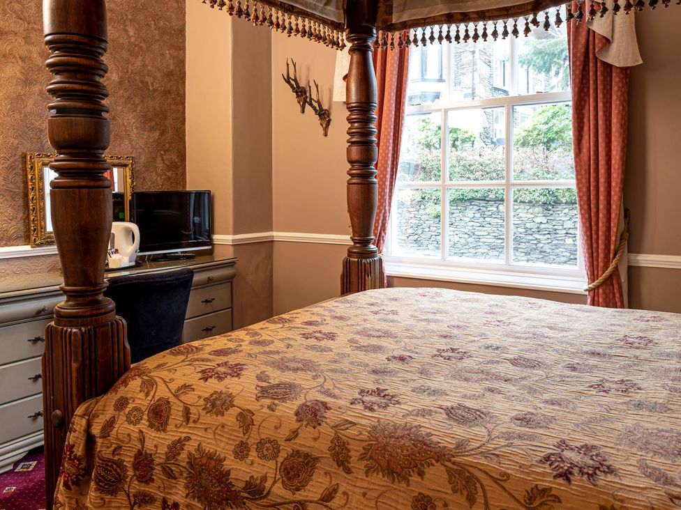 A bedroom featuring a four-poster bed, a TV, and a window at Lonsdale House Bowness-On-Windermere