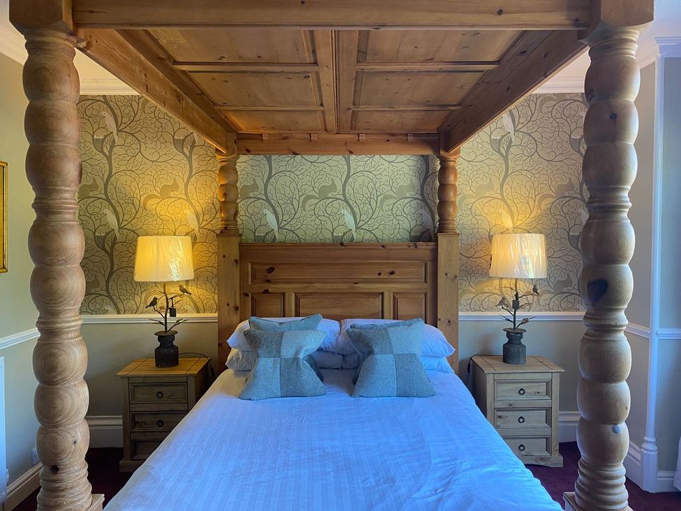 A bedroom with a four-poster bed and bedside tables at Lonsdale House, Bowness-On-Windermere