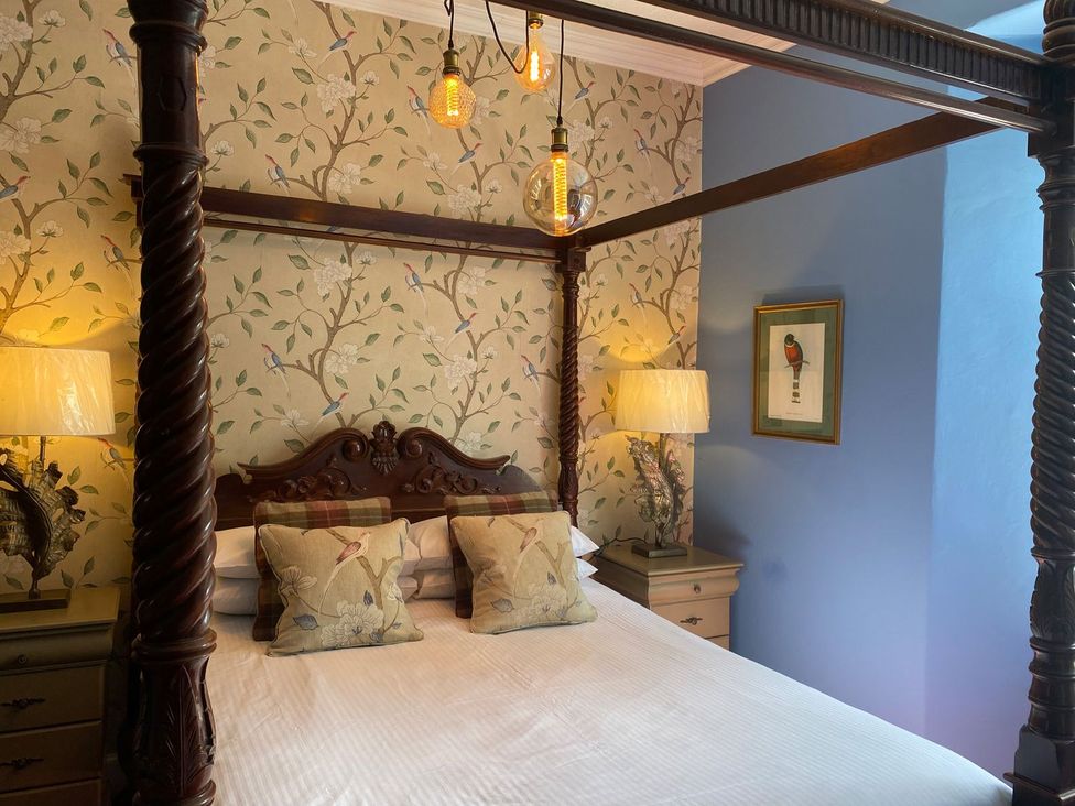 A bedroom with a four-poster bed and lamps at Lonsdale House in Bowness-On-Windermere