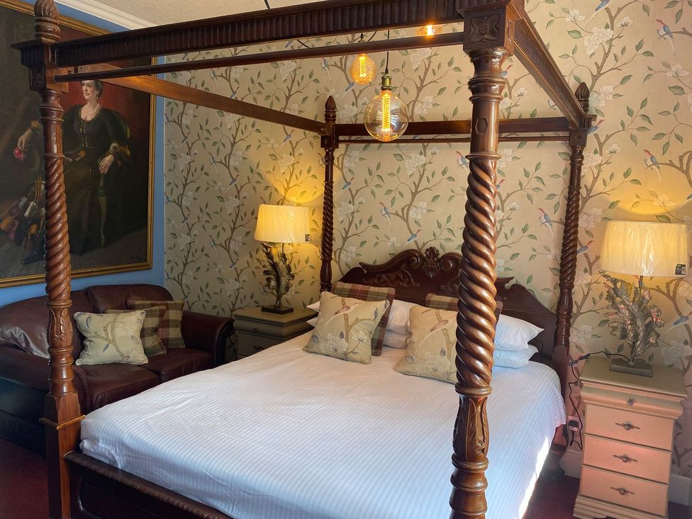 A bedroom featuring a four-poster bed and seating area at Lonsdale House Bowness-On-Windermere