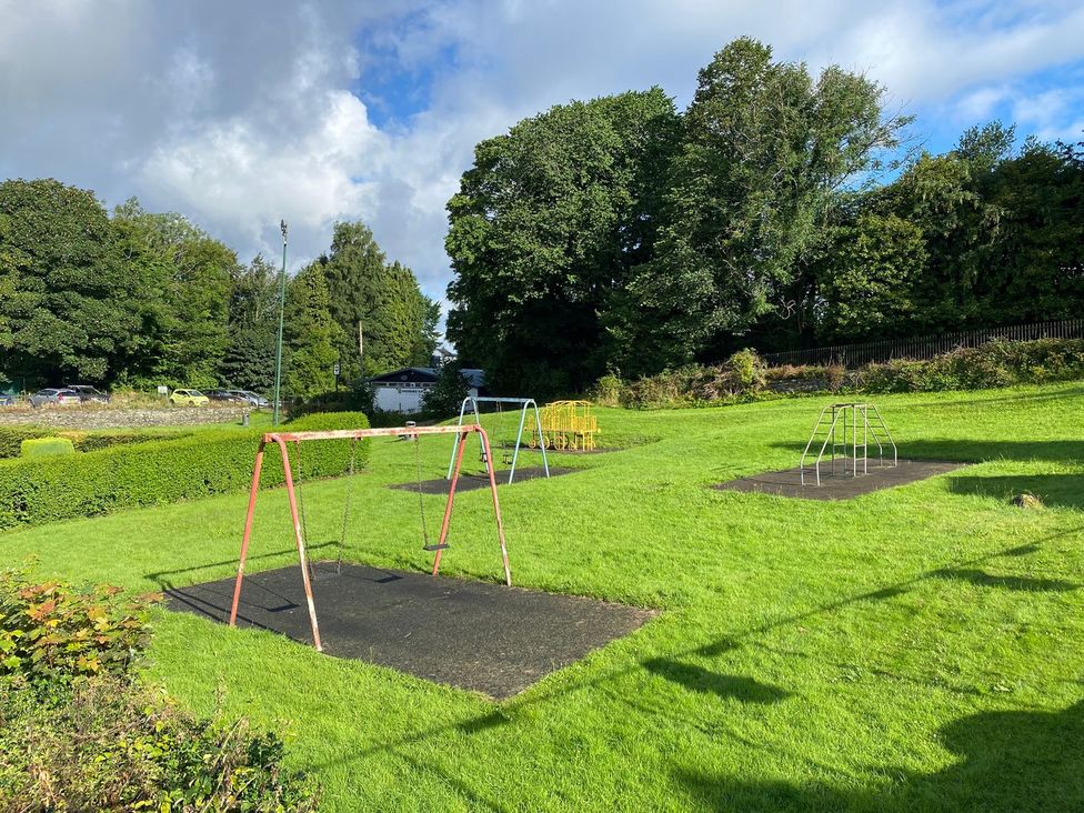 A playground featuring swings and a grassy area at Lonsdale House Bowness-On-Windermere