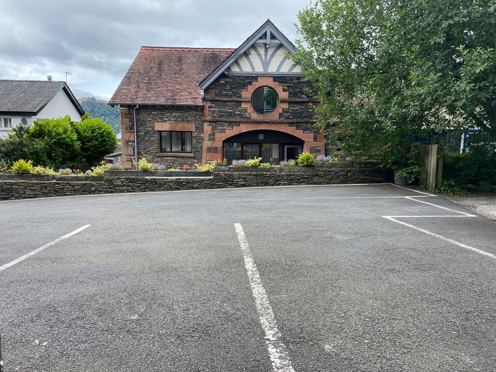 A building with a parking lot and trees at Lonsdale House Bowness-On-Windermere