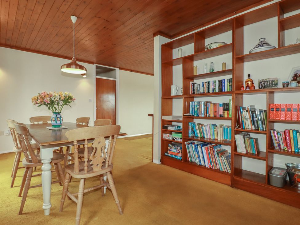 A dining room with a table and bookshelf at 7 Chycoose Parc
