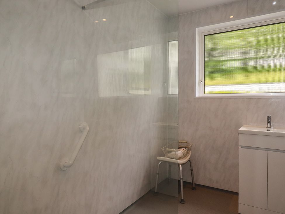 A bathroom with a shower, sink, and stool at 7 Chycoose Parc