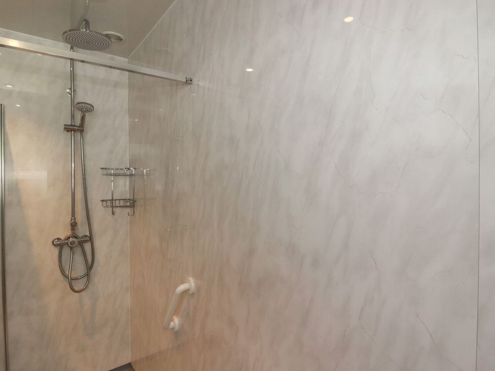A shower area with a showerhead and shelves at 7 Chycoose Parc