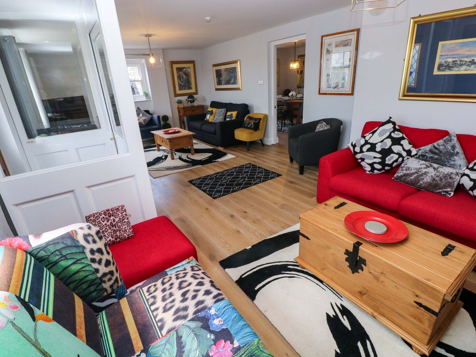 A living room with a red sofa and coffee table at Newgale Cottage in Haverfordwest