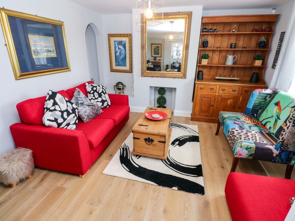 A living room with a red sofa and wooden coffee table at Newgale Cottage in Haverfordwest