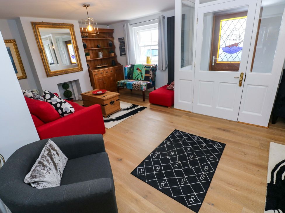A living room with a red sofa and wooden furnishings at Newgale Cottage in Haverfordwest