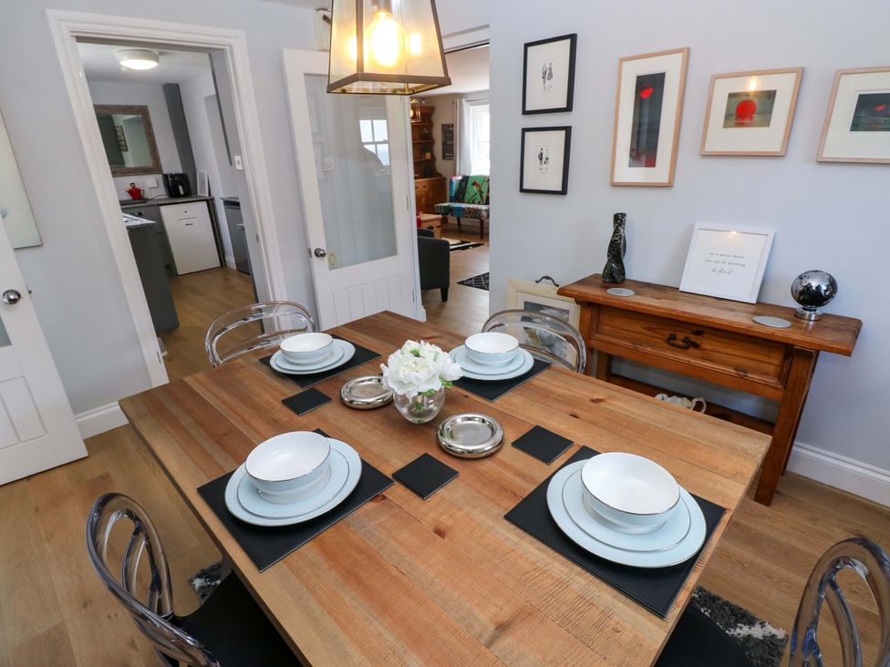 A dining room with a wooden table set for dinner at Newgale Cottage in Haverfordwest