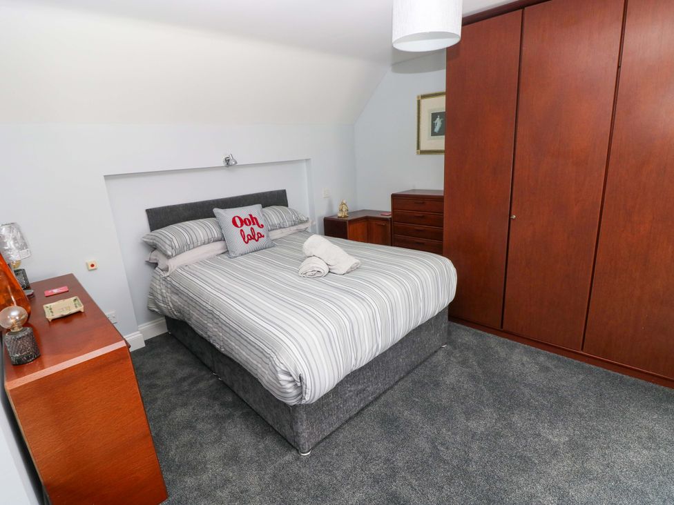 A bedroom with a bed and wardrobe at Newgale Cottage in Haverfordwest