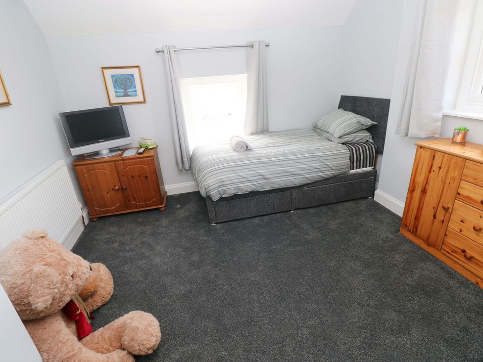 A bedroom with a bed and television at Newgale Cottage Haverfordwest