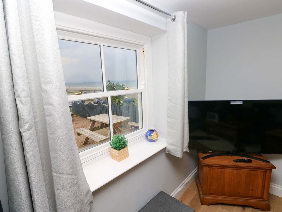 A living room with a window and television at Newgale Cottage in Haverfordwest