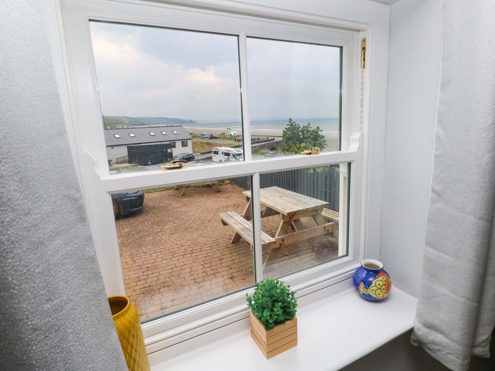 A window view showing a garden seating area and vehicles outside at Newgale Cottage Haverfordwest