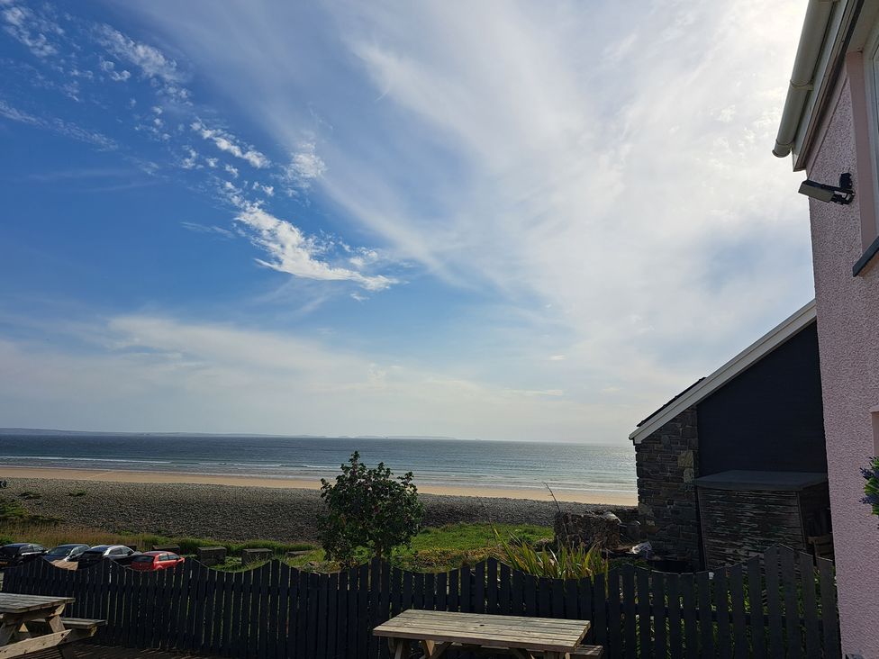 A beach view with tables and ocean at Newgale Cottage in Newgale