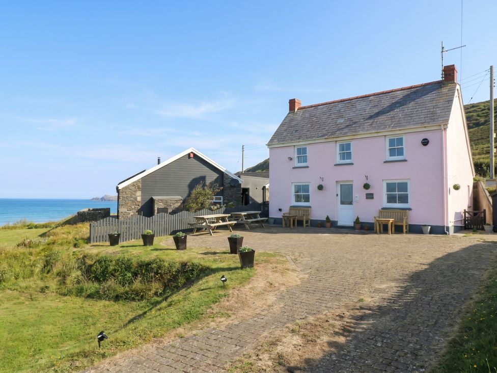 A house and outdoor space with benches and ocean view at Newgale Cottage in Newgale