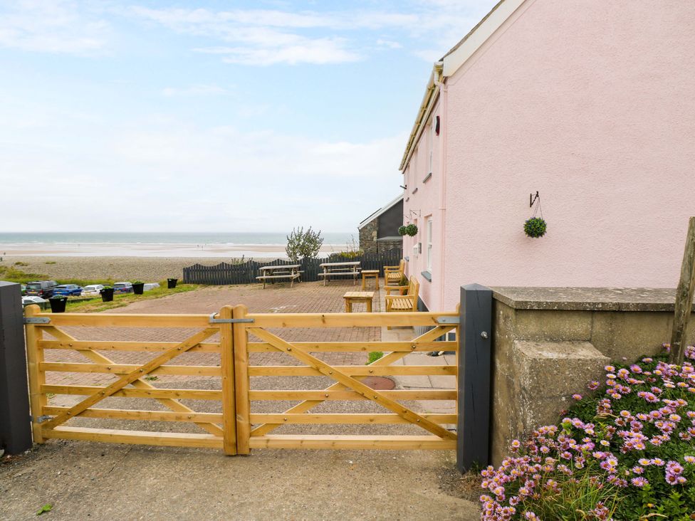 A gate leading to a beach and seating area at Newgale Cottage in Newgale