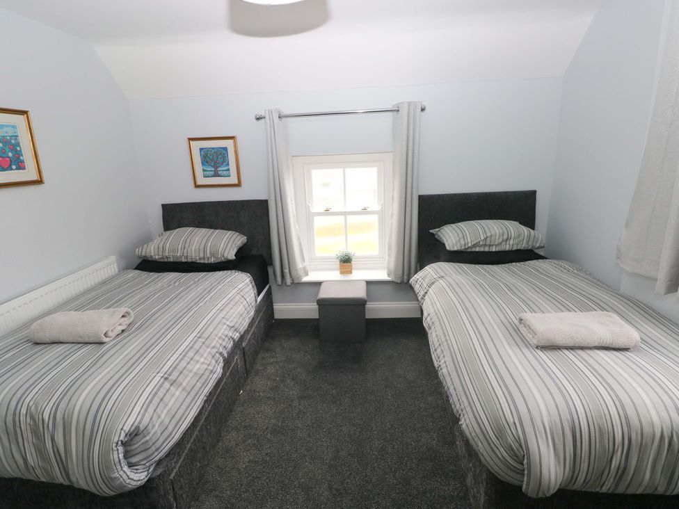 A bedroom with two beds and a window at Newgale Cottage in Newgale