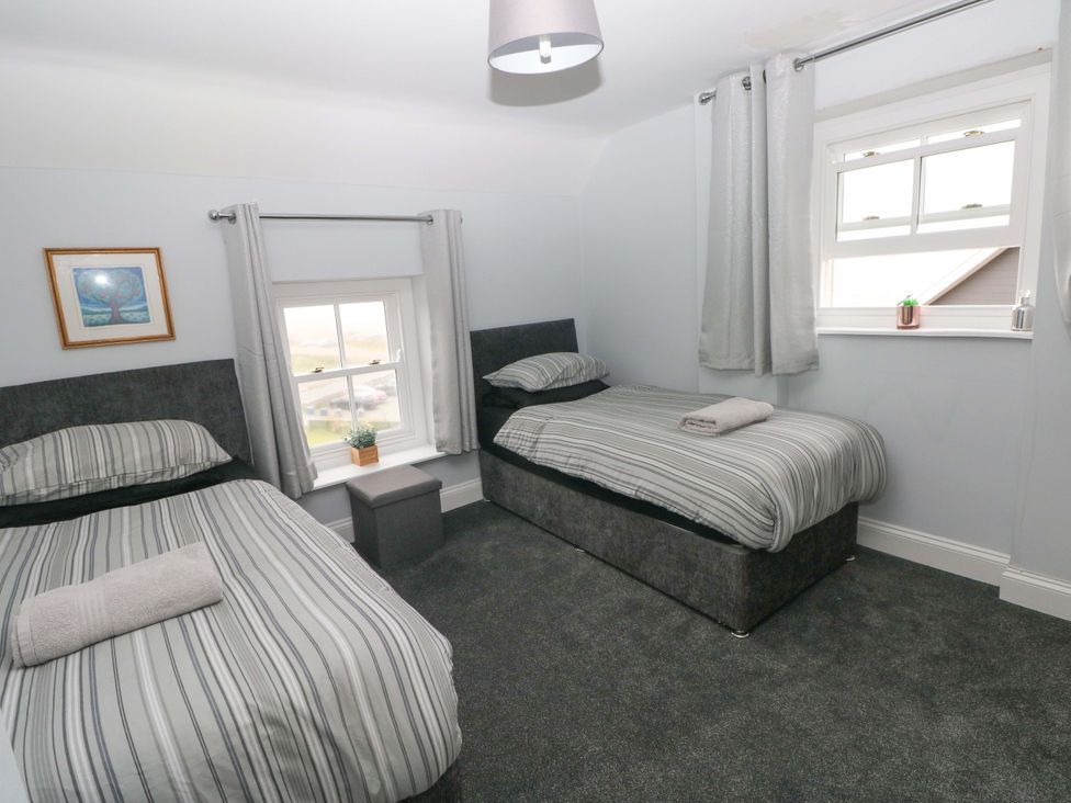 A bedroom with two beds and a window at Newgale Cottage in Newgale