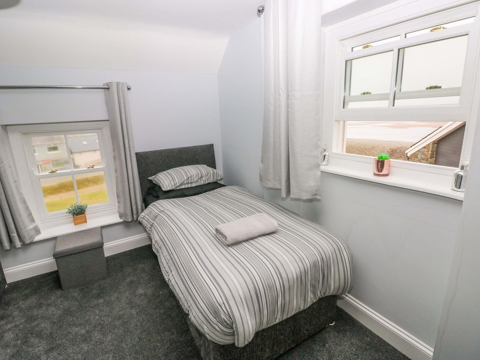A bedroom with a bed and window at Newgale Cottage in Newgale