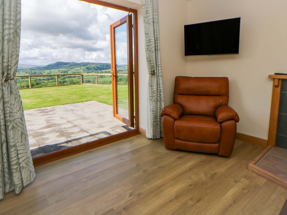 A living room with an armchair and door leading to outdoor space at Yr Onnen