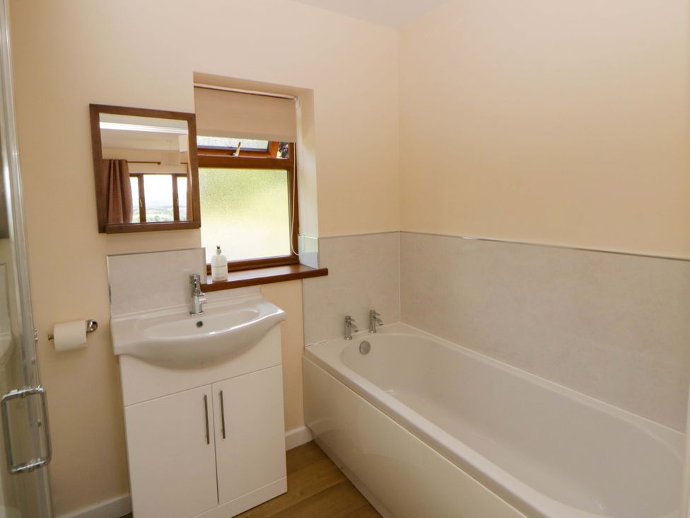 A bathroom with a bathtub, sink, and mirror at Yr Onnen in 