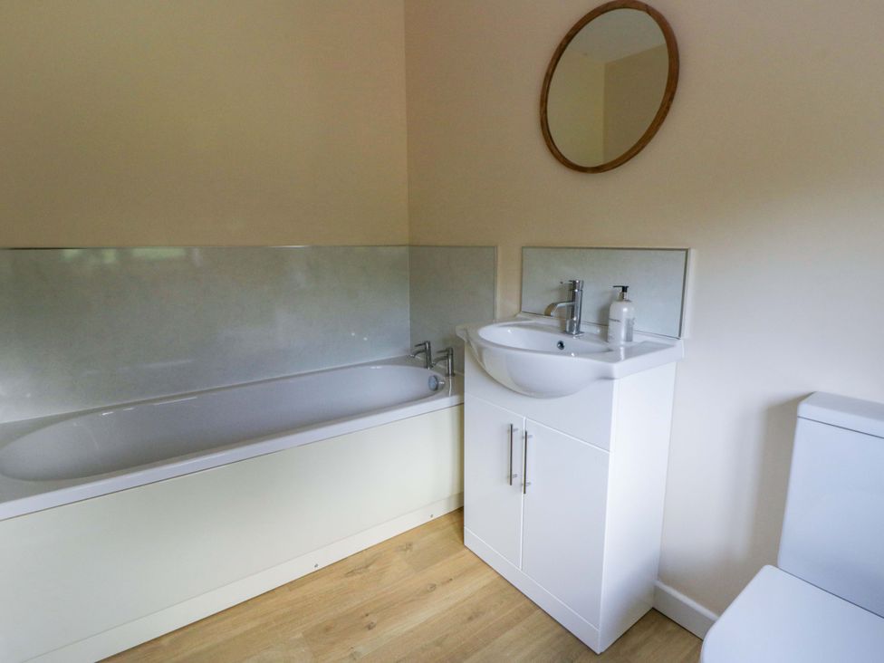 A bathroom with a bathtub, sink, mirror, and toilet at Yr Onnen