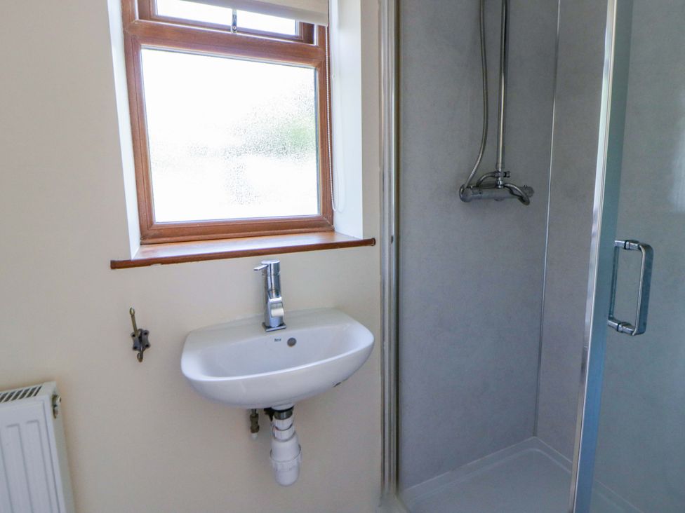 A bathroom with a sink, shower and window at Yr Onnen