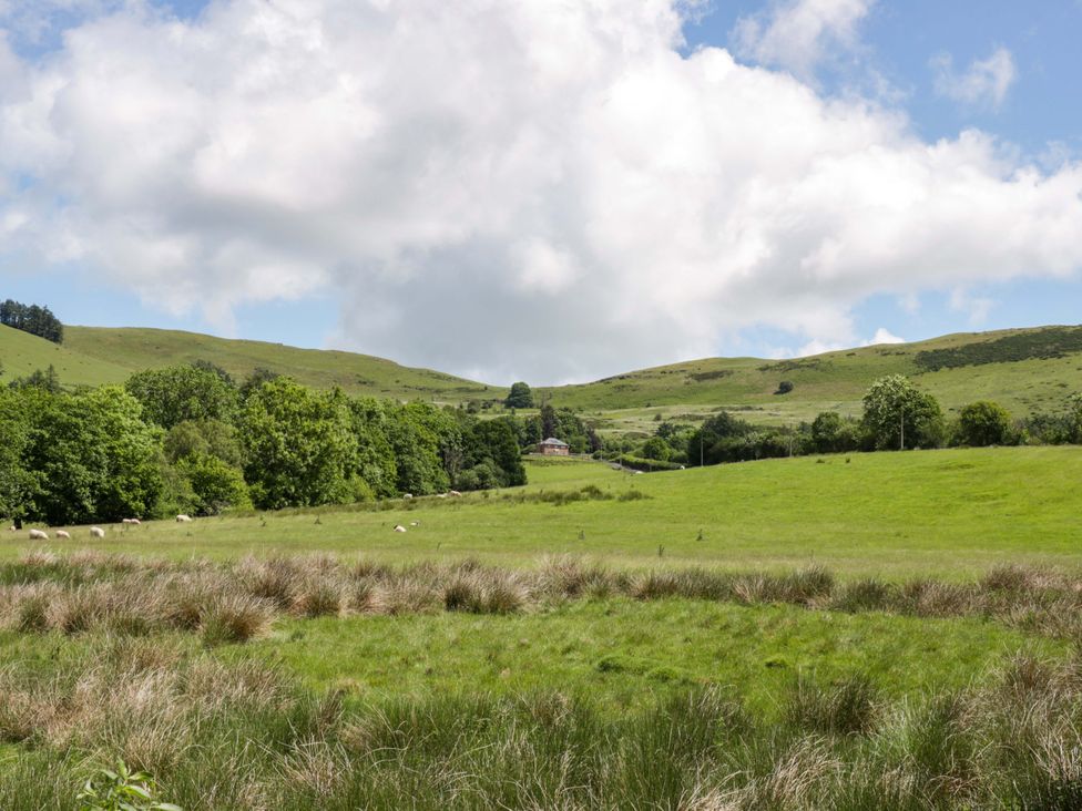 A view of hills and fields with trees and a house at Yr Onnen 