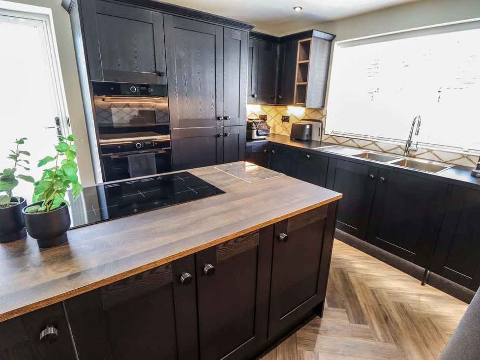 A kitchen with black cabinets and a central island at 21 Anderby road 