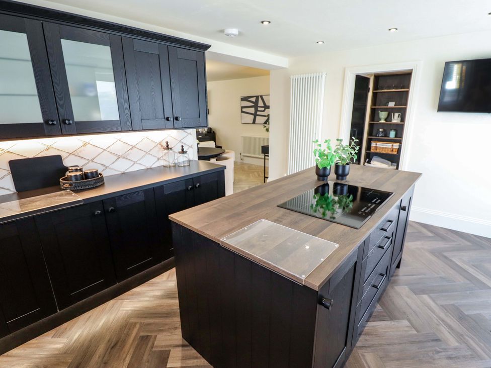 A kitchen with black cabinets and a countertop with stovetop at 21 Anderby road