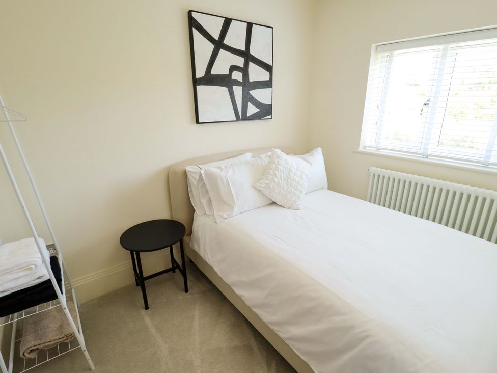 A bedroom with a bed, side table, and artwork at 21 Anderby road