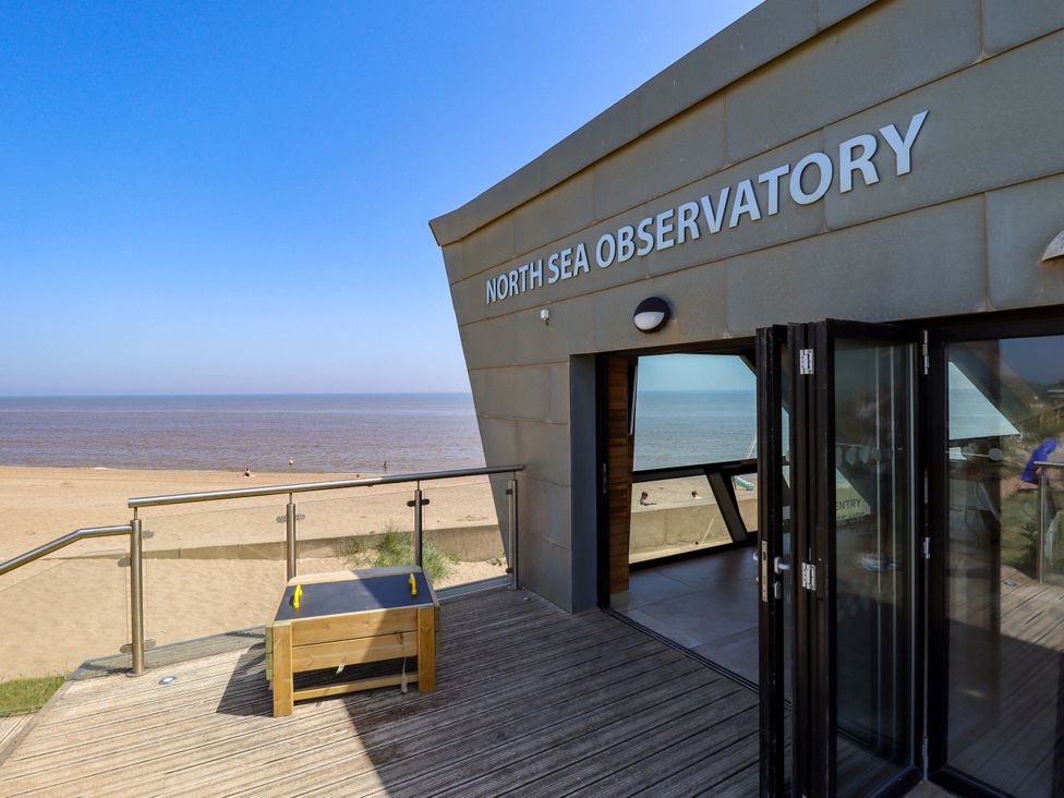 An outdoor deck area at North Sea Observatory with views of the beach and sea