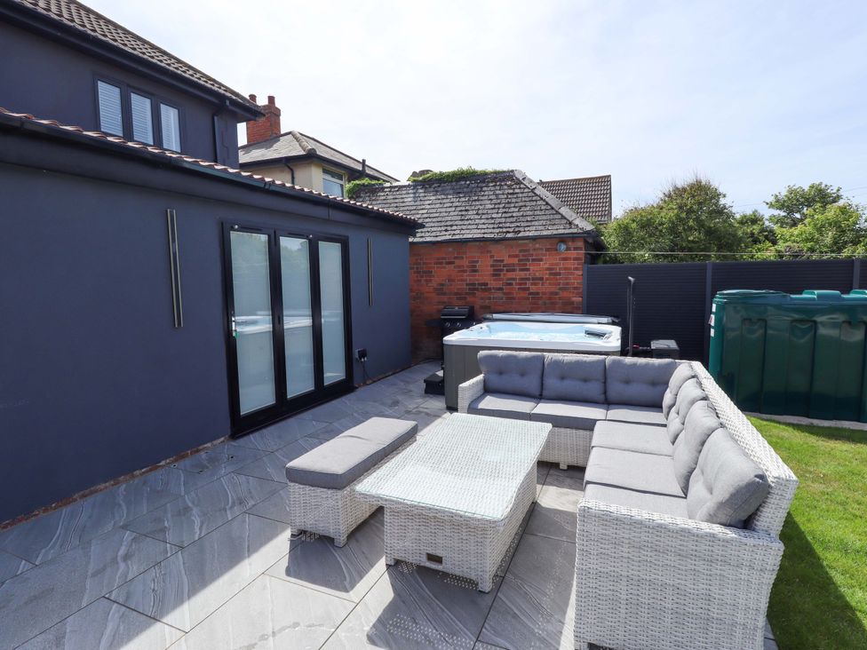An outdoor seating area with a sofa and coffee table next to a hot tub at 21 Anderby Road Chapel St Leonards