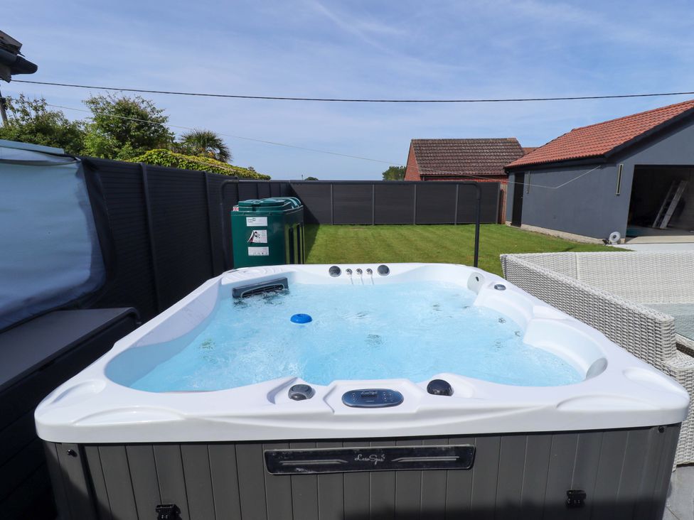 A hot tub with a green bin and patio furniture at 21 Anderby Road, Chapel St Leonards