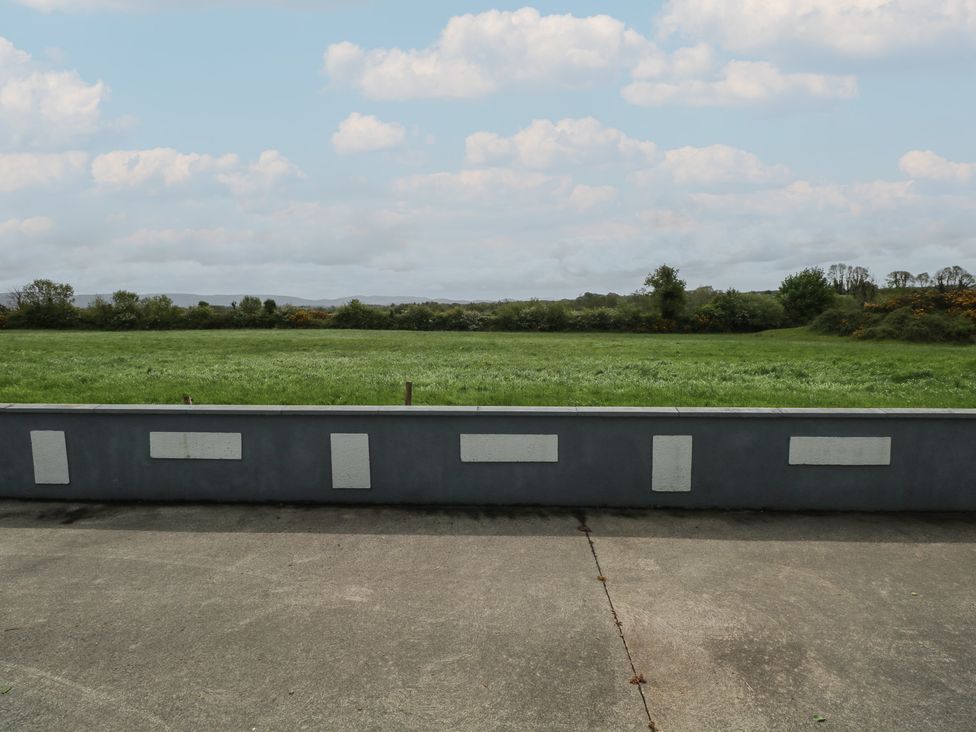 A field with grass and a concrete wall at River House
