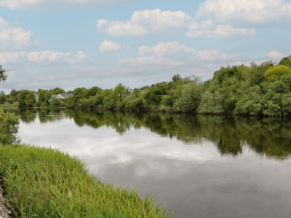 A river with trees and grass under a cloudy sky at River House