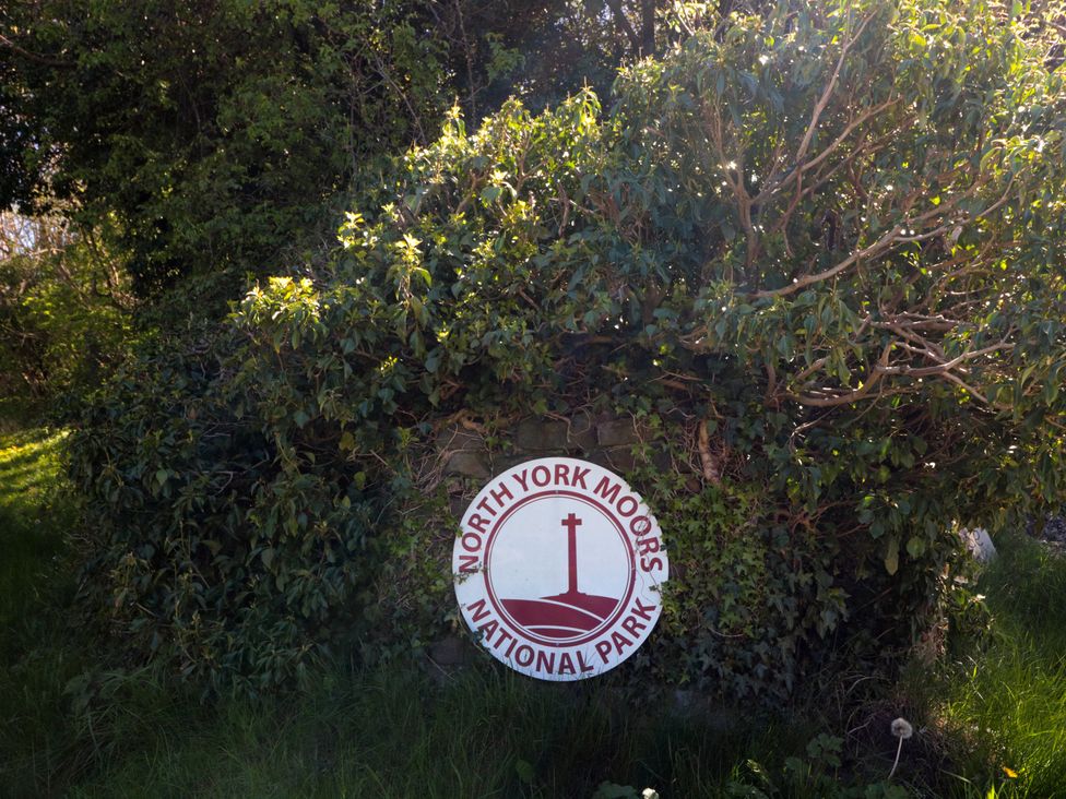 A sign for North York Moors National Park surrounded by bushes and grass