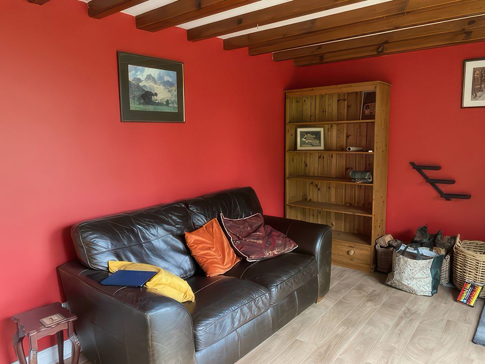 A snug with a leather sofa and wooden bookshelf at The Cottage in Stokesley