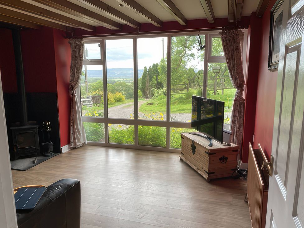 A living room with a television and wood stove at The Cottage in Stokesley