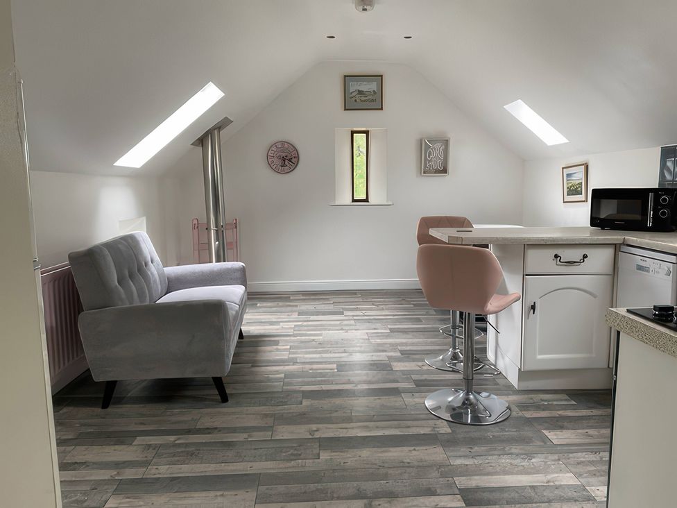 A kitchen with a sofa and bar stools at The Cottage in Stokesley