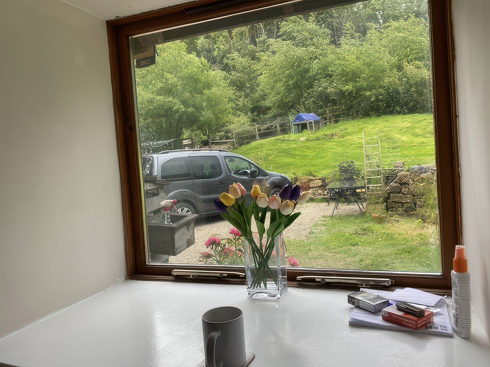 A kitchen window view with flowers and a car outside at The Cottage in Stokesley