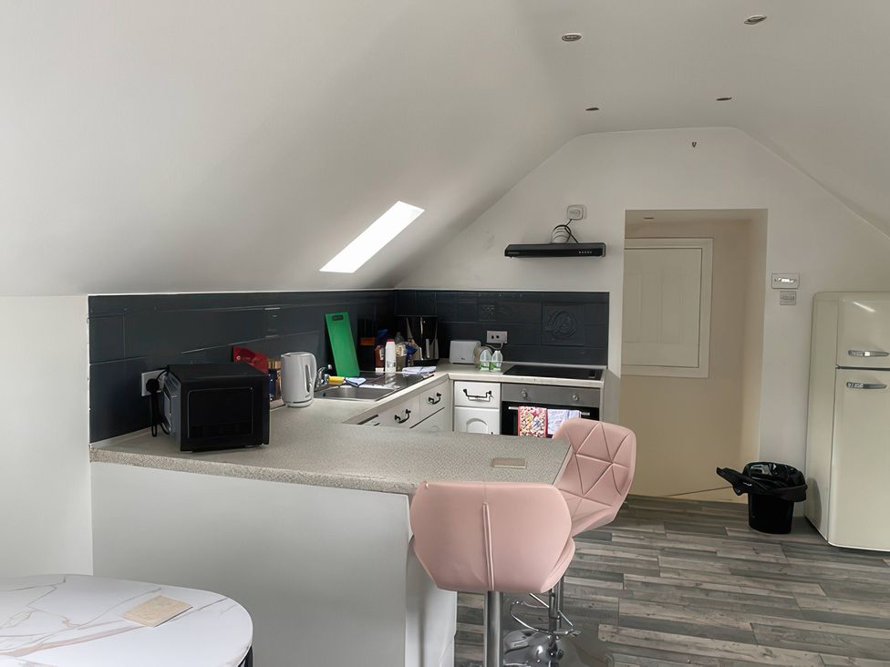 A kitchen with refrigerator and bar stools at The Cottage in Stokesley