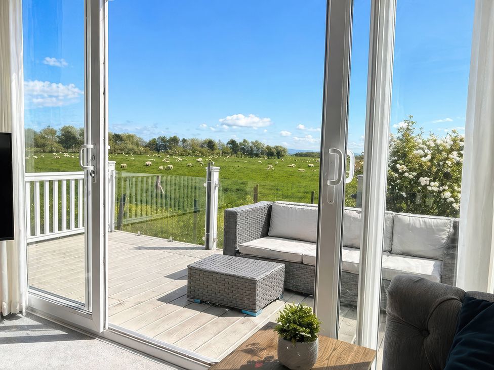 A living room with a view of grass and sheep at Caravan i35 in Conwy